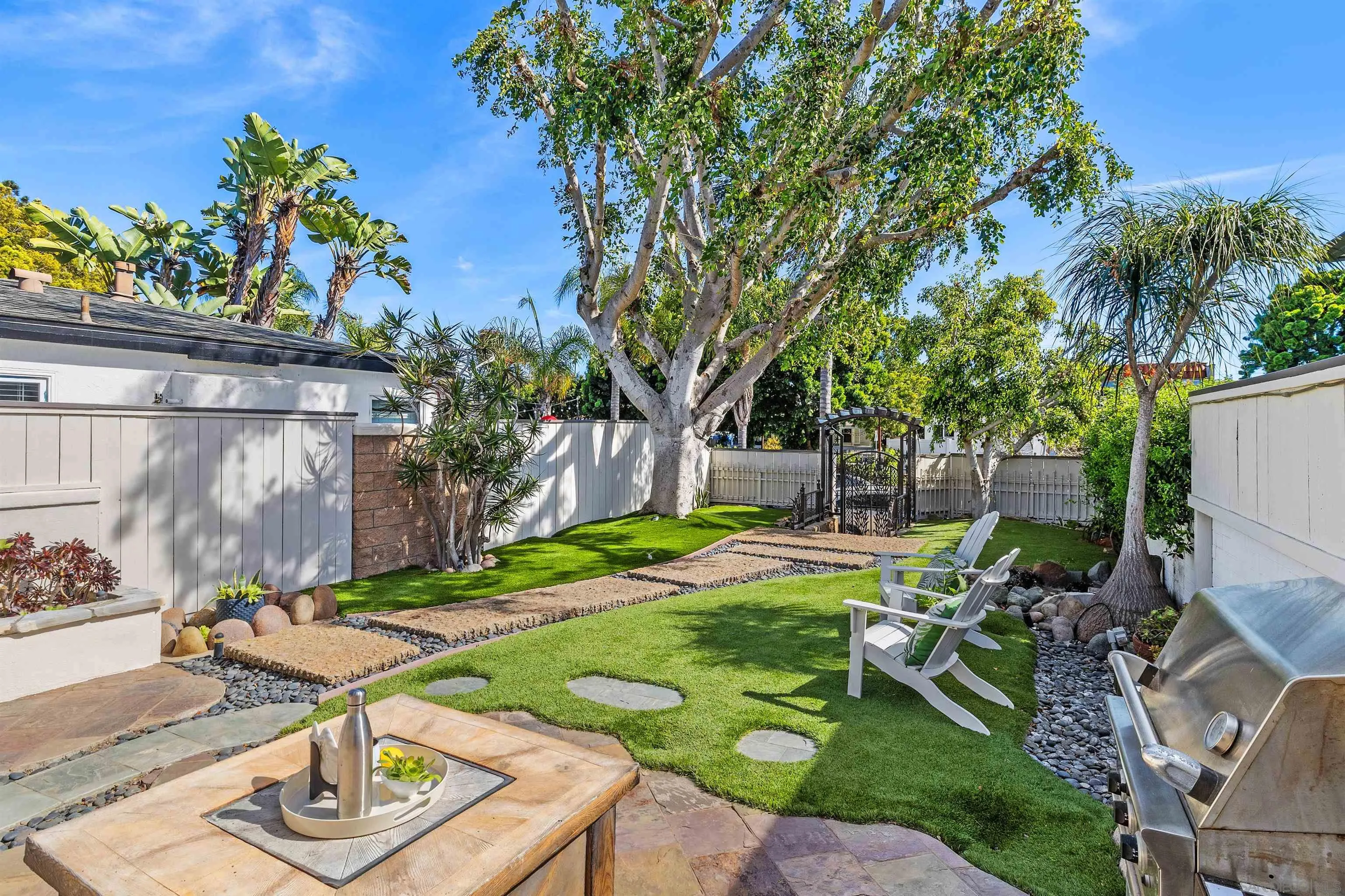 1564 Reed Avenue San Diego, CA 92109 - Photo 4 of 39 Expansive private yard at 1564 Reed Ave, San Diego, CA 92109—rare for Pacific Beach. Lush turf, stone pathways, outdoor lounge, and built-in BBQ create ideal indoor-outdoor living just minutes from the beach, Mission Bay, dining, and coastal lifestyle.