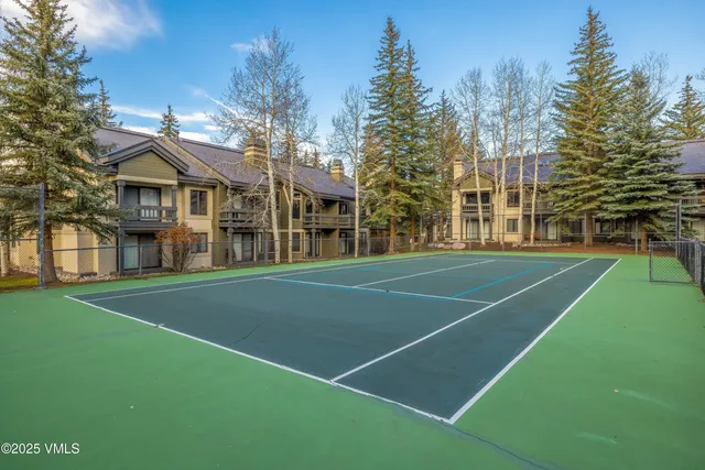 a view of a tennis ground with large trees
