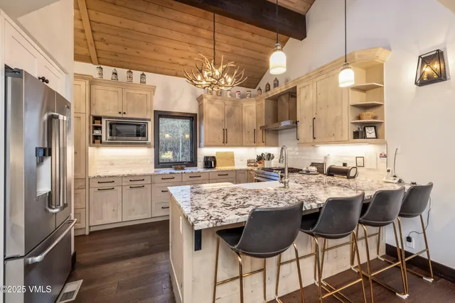 a kitchen with cabinets a counter space stainless steel appliances and a chandelier