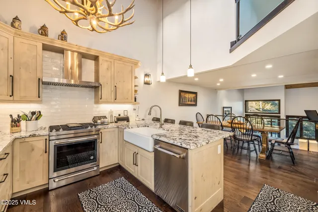 a open kitchen with stainless steel appliances granite countertop a stove top oven a sink dishwasher and white cabinets next to a window