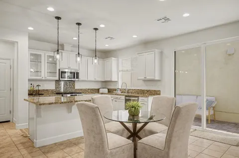 a kitchen with stainless steel appliances granite countertop white cabinets granite counter tops and chairs