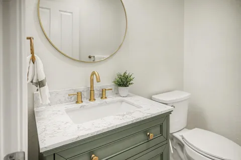 a bathroom with a granite countertop toilet sink and mirror