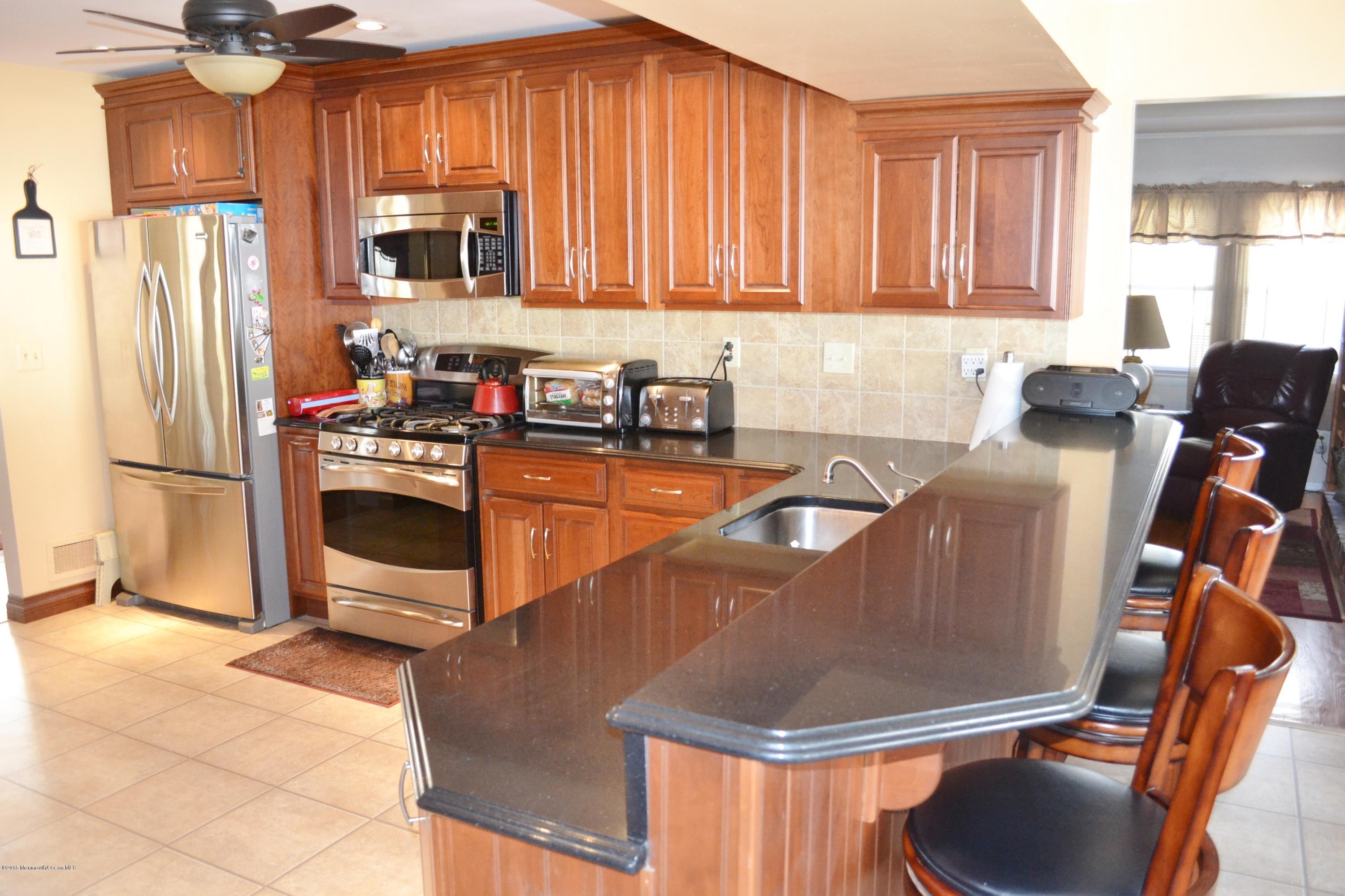 116 Jordan Road Brick, NJ 08724 - Photo 5 of 32 a kitchen with stainless steel appliances granite countertop a refrigerator a stove a sink a dining table and chairs with wooden floor
