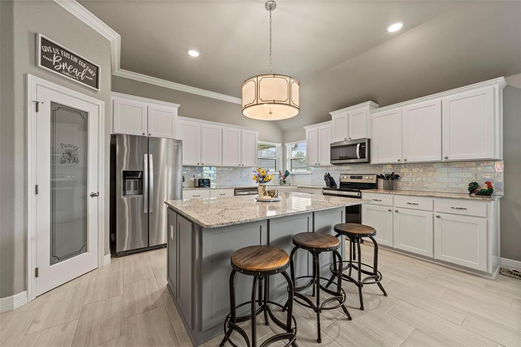 828 Agile Street Hewitt, TX 76643 - Photo 11 of 30 a kitchen with stainless steel appliances kitchen island granite countertop a table chairs microwave and refrigerator