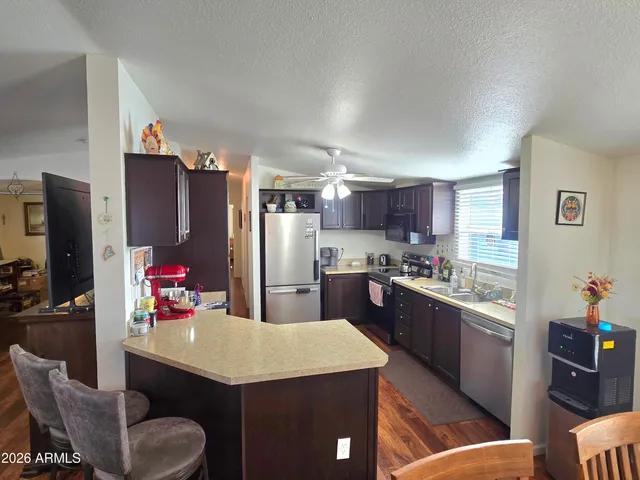 a kitchen with stainless steel appliances kitchen island granite countertop a refrigerator a stove top oven a sink dishwasher and white cabinets with wooden floor