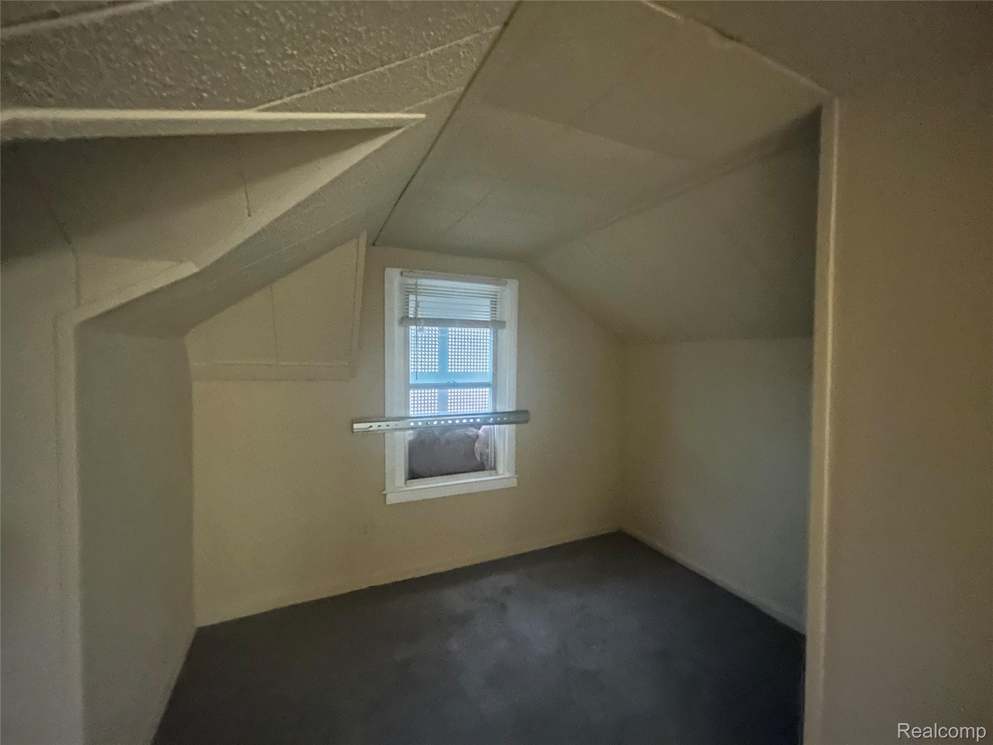 16824 Rutherford Street Detroit, MI 48235 - Photo 12 of 25 Room featuring an angled ceiling, window with blinds, and dark carpeting