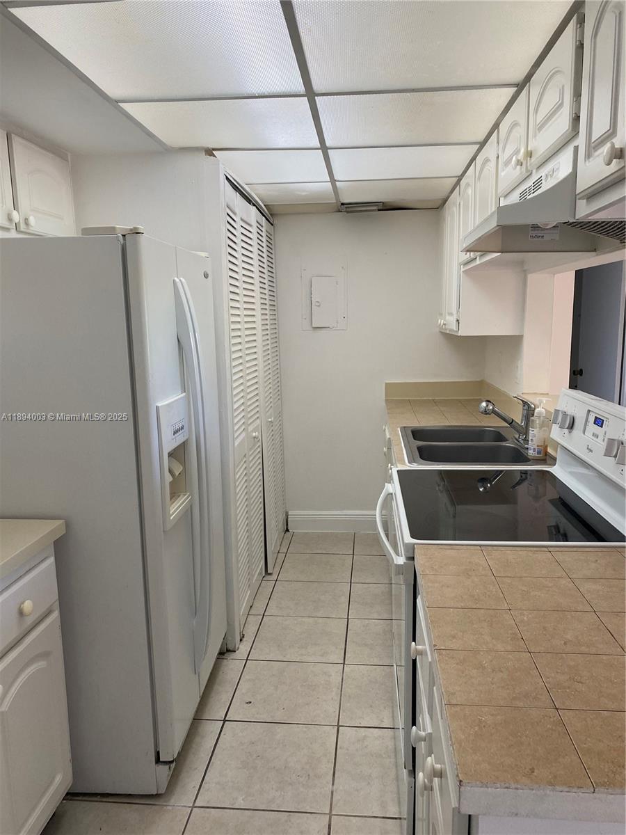 4453 Treehouse Lane, Unit C Tamarac, FL 33319 - Photo 16 of 21 a kitchen with a stove a refrigerator and a sink