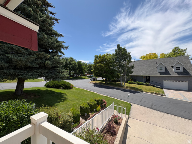 595 Meadowlark Road Orem, UT 84097 - Photo 74 of 87 Suburban landscape featuring a well-maintained lawn, mature trees, and a paved driveway leading to a two-car garage