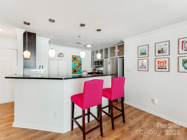 a kitchen with stainless steel appliances granite countertop a dining table chairs and a refrigerator