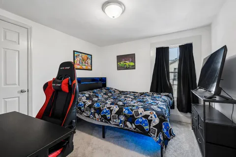 a bedroom with a bed and a flat tv screen on a dresser