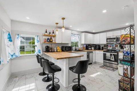 a kitchen with white cabinets and chairs