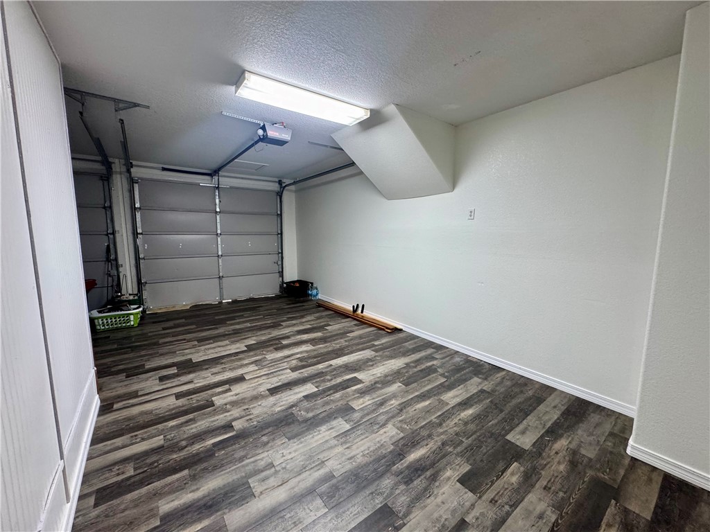 1197 Ridgeview Lane Russellville, AR 72802 - Photo 31 of 44 Spacious garage featuring a roll-up door, wood-finish flooring, white painted walls, and overhead fluorescent lighting
