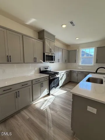a kitchen with a sink a stove top oven and cabinets
