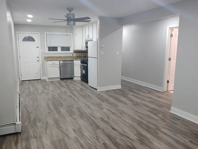 a kitchen with wooden floors and white cabinets
