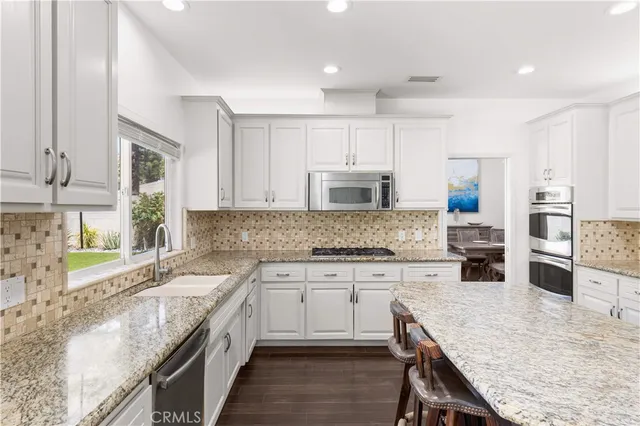 a kitchen with stainless steel appliances granite countertop a stove refrigerator sink and microwave