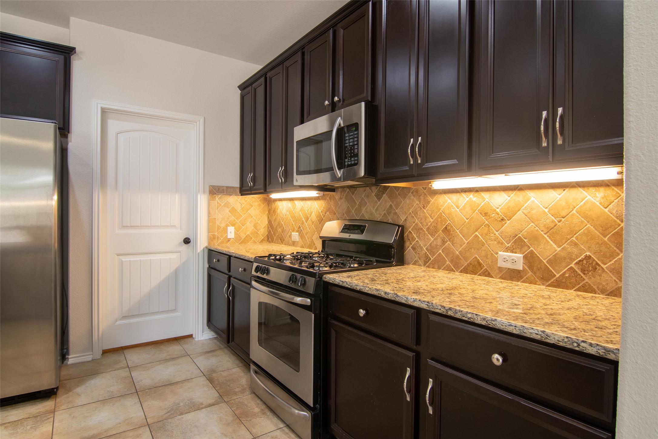 12104 Broten Street Austin, TX 78748 - Photo 10 of 32 Culinary delights await in this modern kitchen with granite countertops and dark cabinetry.