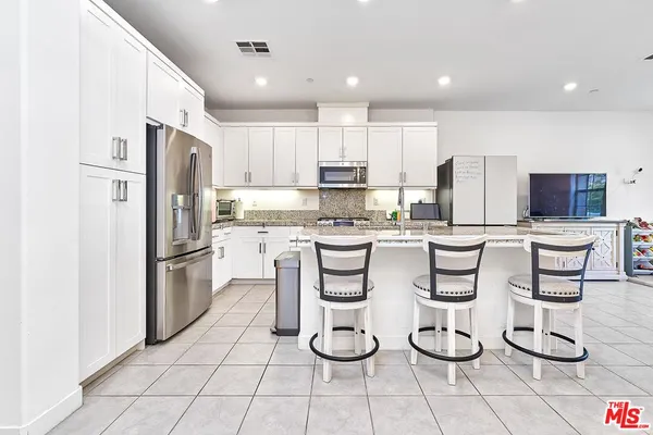 a kitchen with stainless steel appliances granite countertop a refrigerator and white cabinets