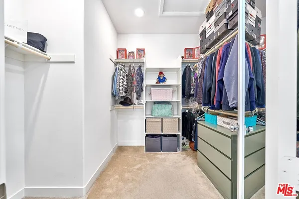 a view of walk in closet with clothes and shoes