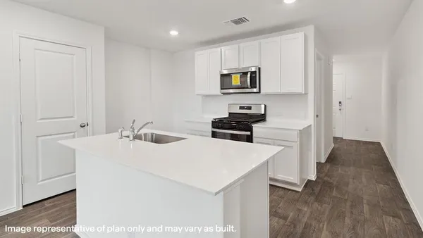 a kitchen with a sink a stove and white cabinets