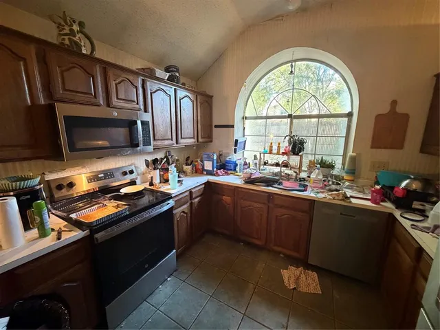 a kitchen that has a sink cabinets appliances and a window