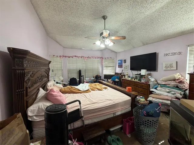 a bed room with a bed a flat screen tv and a chandelier