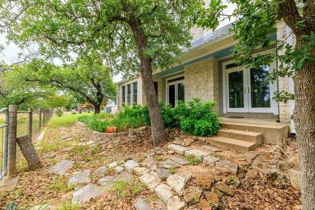a view of a house with a small yard and large tree