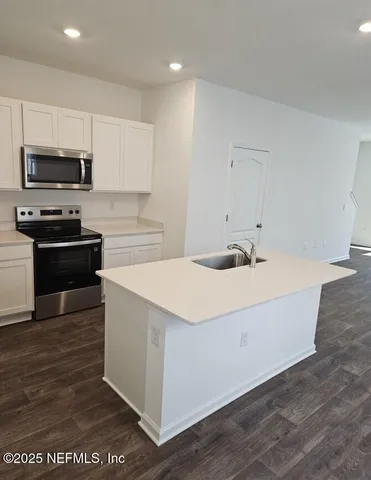 a kitchen with stainless steel appliances a sink a stove top oven a counter space and cabinets