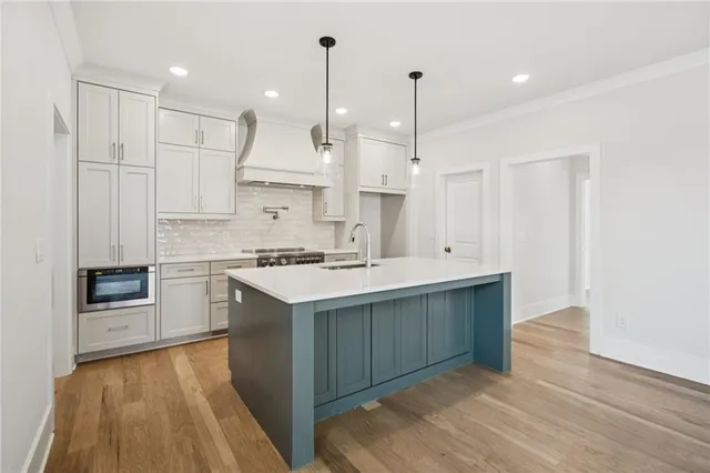 a kitchen with stainless steel appliances a stove a refrigerator a sink and white cabinets