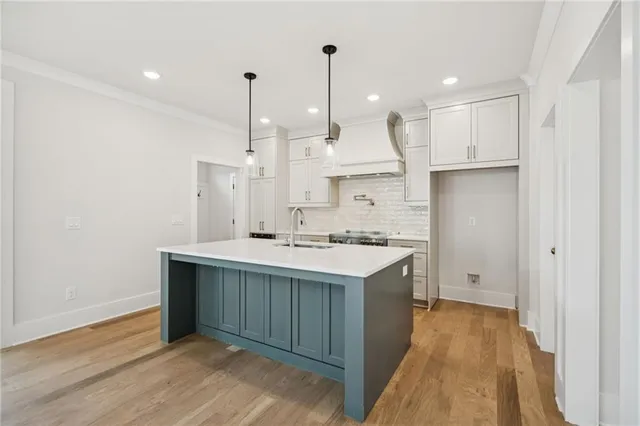 a kitchen that has a sink and a stove with wooden floor