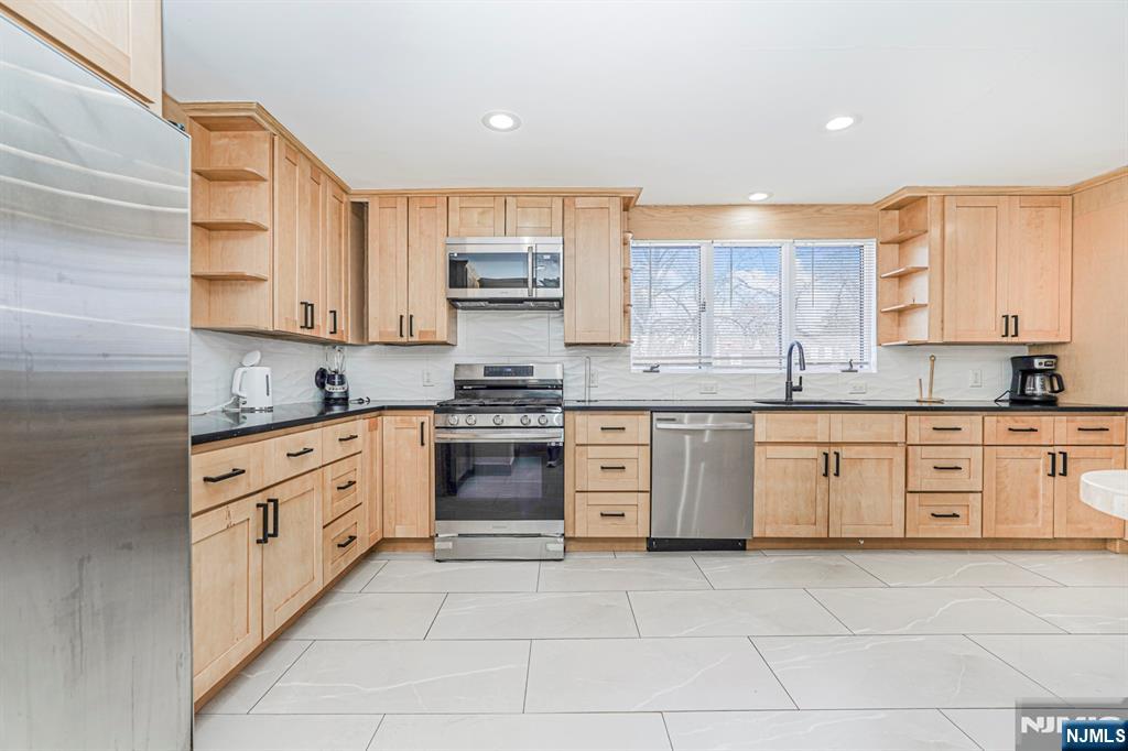 566 Teaneck Road Teaneck, NJ 07666 - Photo 13 of 35 a kitchen with stainless steel appliances a stove sink and cabinets