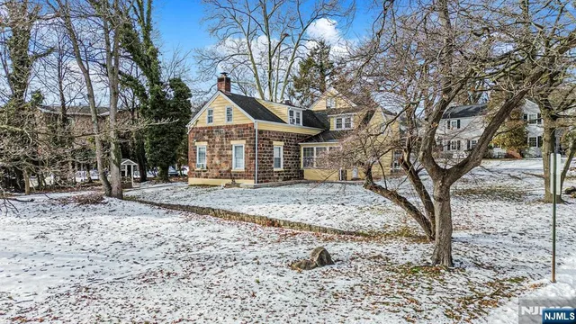 a view of a house with a yard and large trees