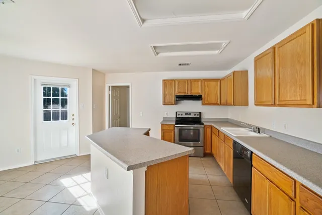 a kitchen with a sink a stove top oven a refrigerator cabinets and a window