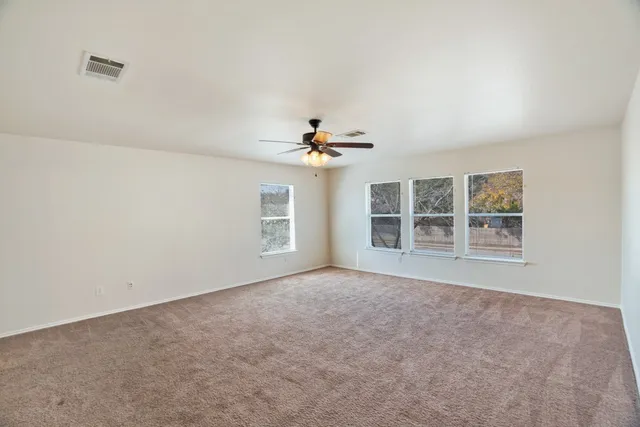 an empty room with windows and chandelier fan