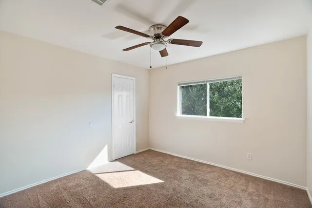 an empty room with a window and a fan