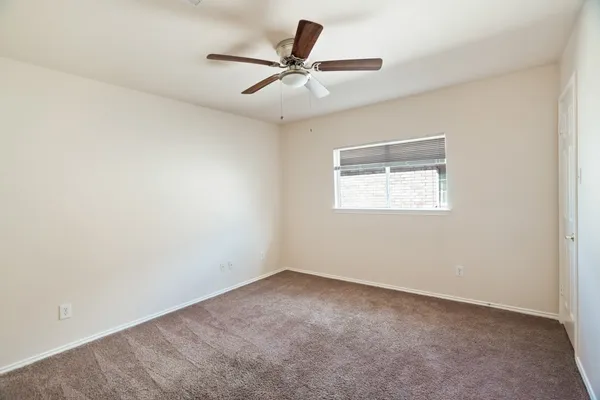 an empty room with a window and a ceiling fan