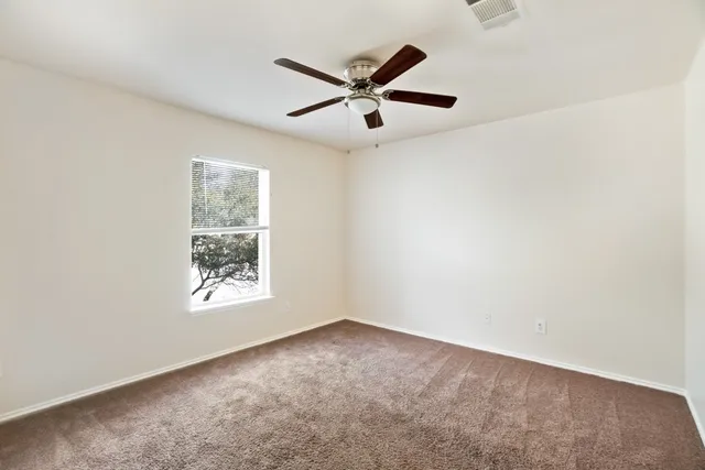 an empty room with window and ceiling fan
