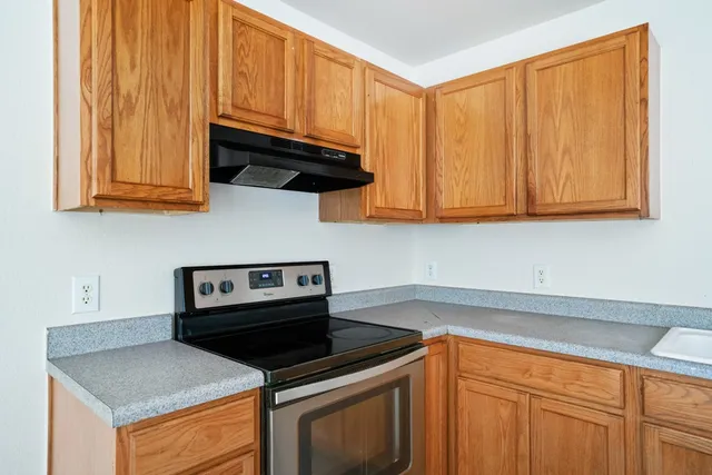 a kitchen with wooden cabinets and a stove top oven