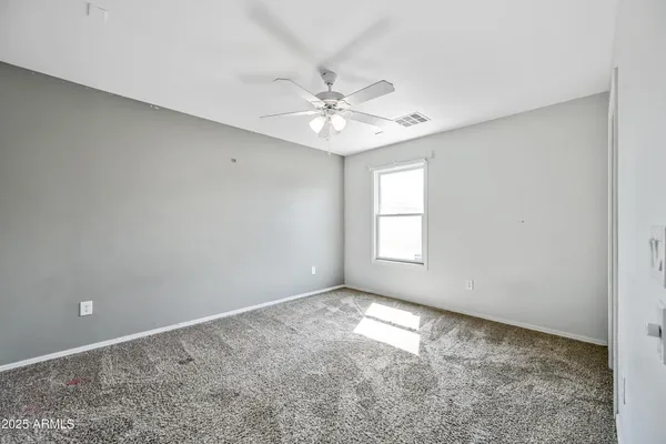 an empty room with windows and fan