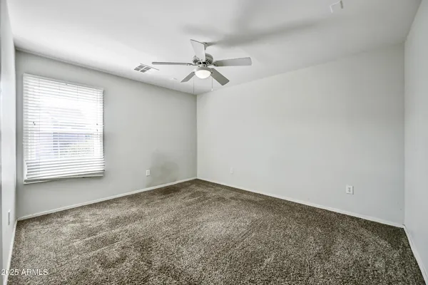 an empty room with windows and ceiling fan