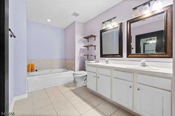 a bathroom with a bathtub a double vanity sink and mirror