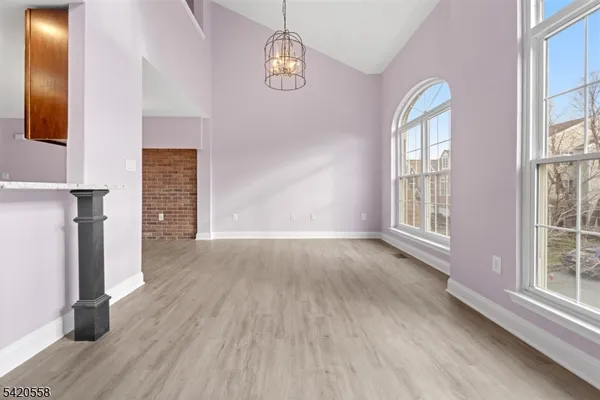 an empty room with wooden floor mirror and windows