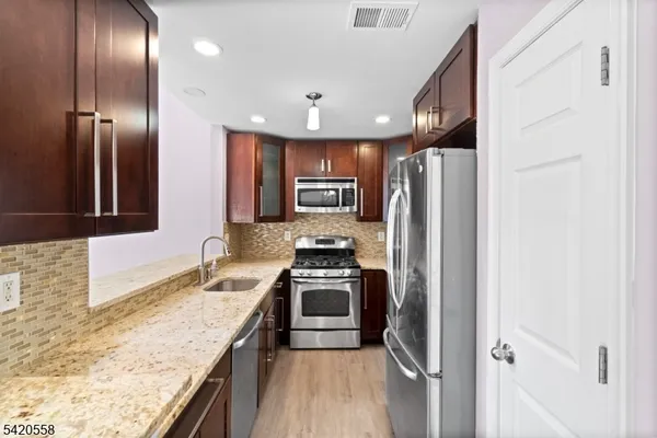 a kitchen with granite countertop stainless steel appliances and wooden cabinets