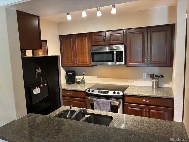 a kitchen with kitchen island granite countertop a stove refrigerator and microwave