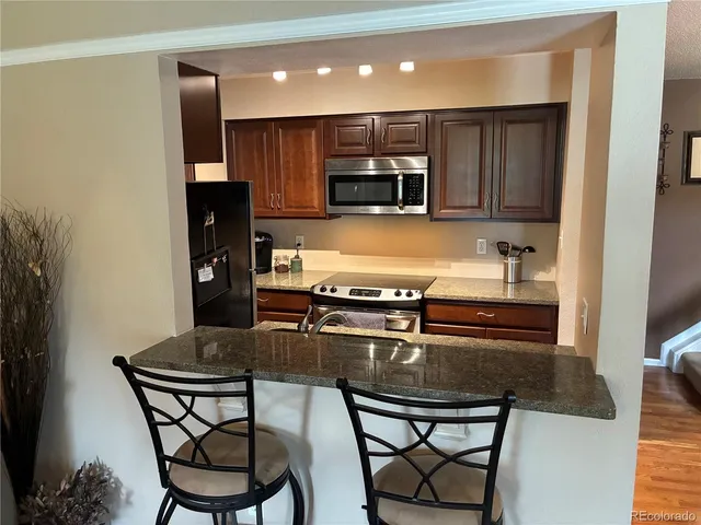a kitchen with kitchen island granite countertop a stove and a refrigerator with cabinets