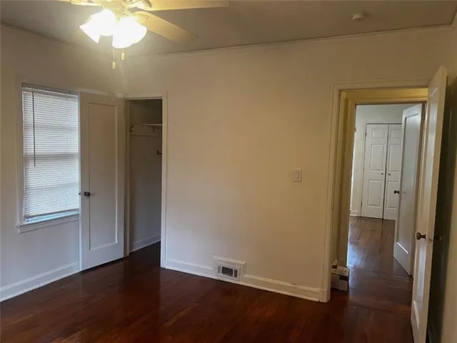 an empty room with wooden floor cabinet and windows