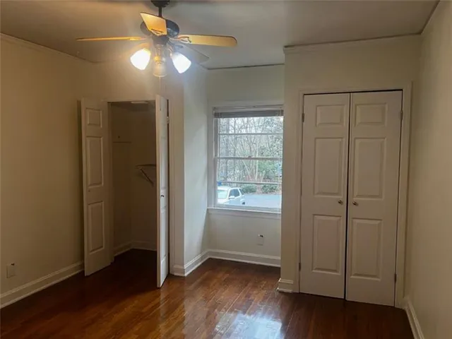 an empty room with wooden floor closet and windows