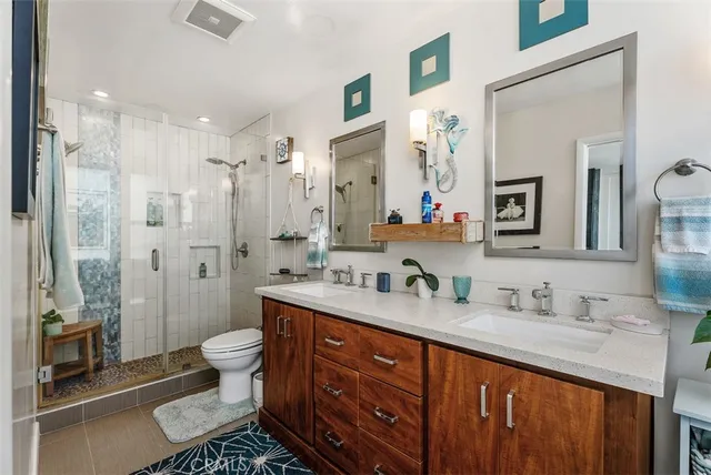 a bathroom with a double vanity sink toilet mirror and shower