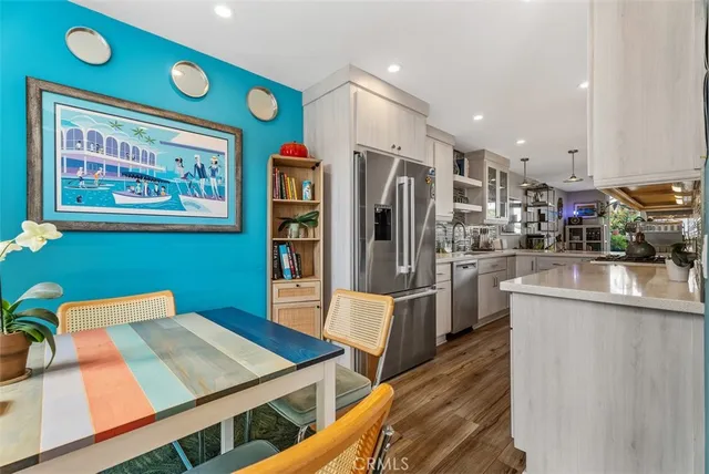 a kitchen with stainless steel appliances kitchen island granite countertop a refrigerator and a wooden floors