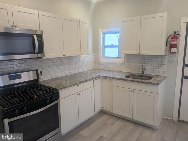 a kitchen with granite countertop white cabinets and stainless steel appliances