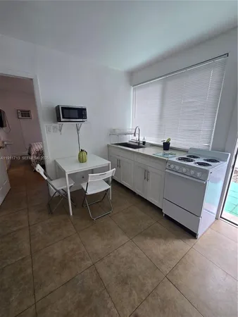 a room with a chair and white cabinets